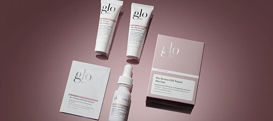 glo skincare tubes, dropper bottle, box and sachet arranged on a mauve background