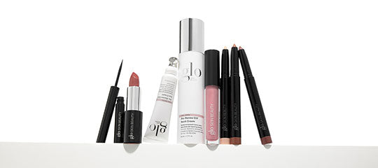 Assorted glo cosmetic products: liquid eyeliner, lipstick, skincare tube, lip gloss, and three lip liners on white surface.