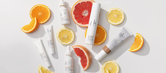 Skincare products with slices of orange, lemon, and grapefruit on white background