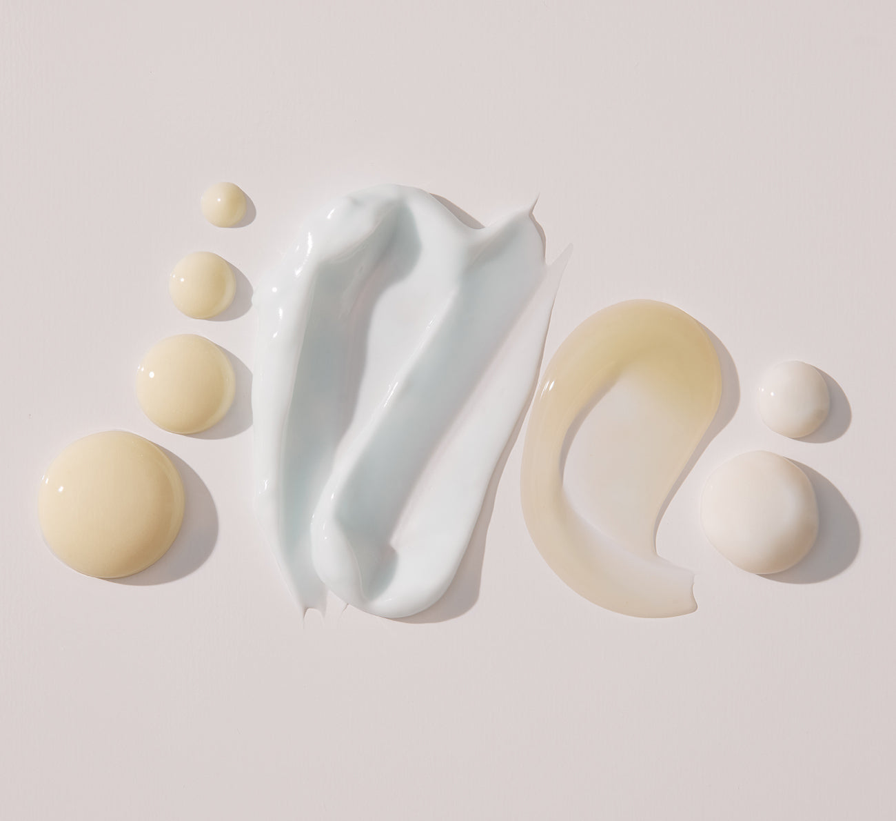 Skincare swatches and droplets next to Key Ingredients: pale blue cream smear, translucent beige gel smear and beige/white drops on pink background